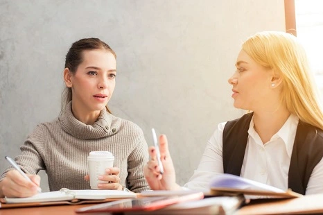 Deux jeunes femmes souriantes discutant dans un bureau conviviale